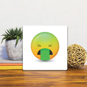A Slidetile of the Stomach Sick Emoji sitting on a table.