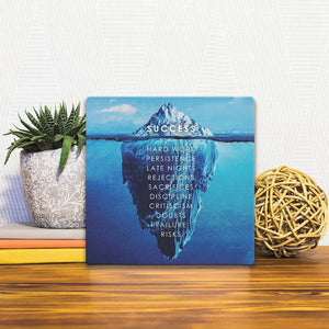 A Slidetile of the Iceberg of Success sitting on a table.