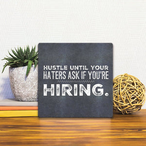 A Slidetile of the Hustle till your hiring… sitting on a table.
