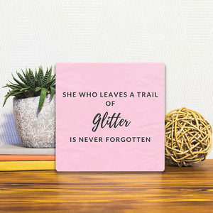 A Slidetile of the She who leaves a trail of glitter… sitting on a table.