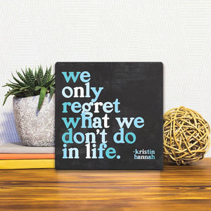 A Slidetile of the We Only Regret What We Don't Do sitting on a table.