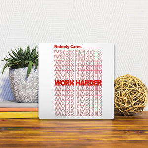 A Slidetile of the Work harder… sitting on a table.