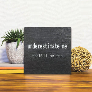 A Slidetile of the Underestimate Me sitting on a table.