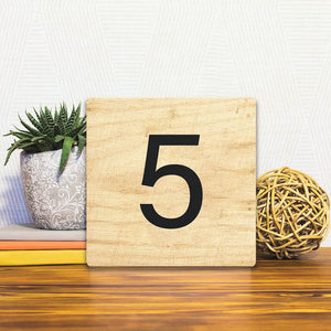 A Slidetile of the Number 5 - Light Wood sitting on a table.