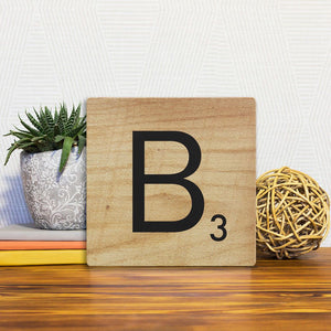 A Slidetile of the Letter B - Light Wood sitting on a table.