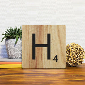 A Slidetile of the Letter H - Light Wood sitting on a table.