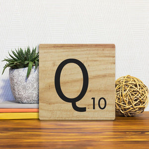 A Slidetile of the Letter Q - Light Wood sitting on a table.