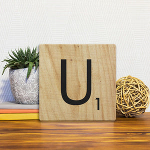A Slidetile of the Letter U - Light Wood sitting on a table.