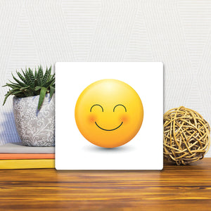 A Slidetile of the Delighted Emoji sitting on a table.