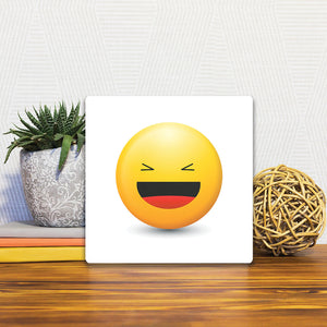 A Slidetile of the Laughing Emoji sitting on a table.