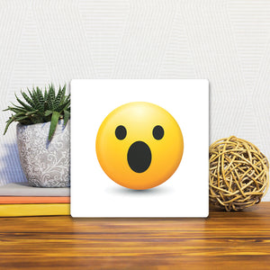 A Slidetile of the Shocked Emoji sitting on a table.