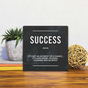 A Slidetile of the Definition of Success sitting on a table.