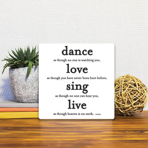 A Slidetile of the Dance, love, sing, live sitting on a table.