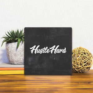 A Slidetile of the Hustle Hard sitting on a table.