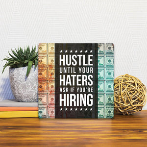 A Slidetile of the Hustle until your haters… sitting on a table.
