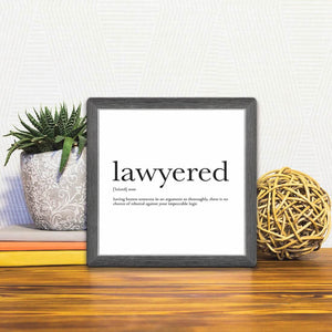 A Slidetile of the Definition of Lawyered sitting on a table.