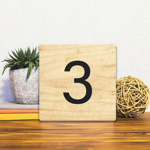 A Slidetile of the Number 3 - Light Wood sitting on a table.