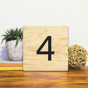 A Slidetile of the Number 4 - Light Wood sitting on a table.