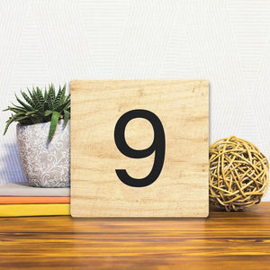 A Slidetile of the Number 9 - Light Wood sitting on a table.