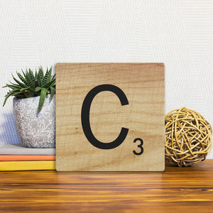 A Slidetile of the Letter C - Light Wood sitting on a table.