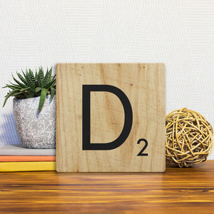 A Slidetile of the Letter D - Light Wood sitting on a table.