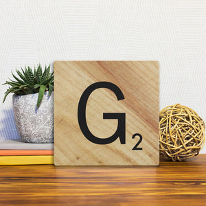A Slidetile of the Letter G - Light Wood sitting on a table.