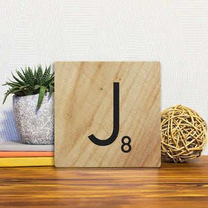 A Slidetile of the Letter J - Light Wood sitting on a table.