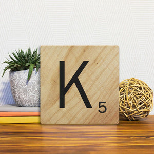 A Slidetile of the Letter K - Light Wood sitting on a table.