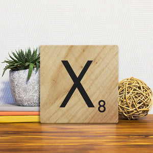 A Slidetile of the Letter X - Light Wood sitting on a table.
