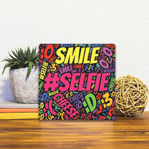 A Slidetile of the Selfie: Smile Say Cheese sitting on a table.
